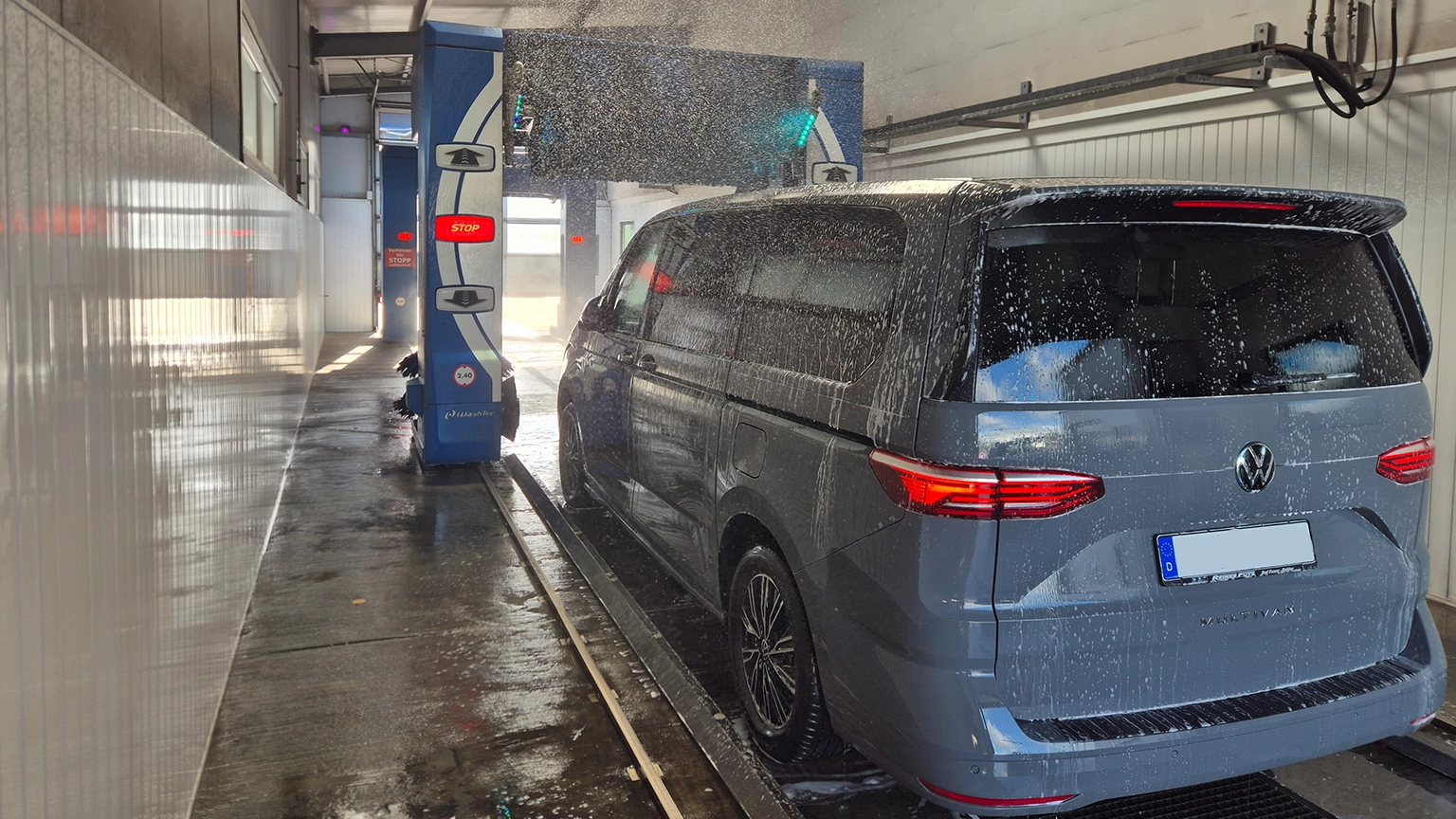 Grauer VW Multivan während der Wäsche in der blauen Portalwaschanlage